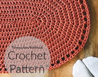 Puede incluir: Un primer plano de una alfombra de crochet de color naranja quemado. La alfombra tiene un borde festoneado y está hecha con un hilo grueso. El texto "Brenna Ann Handmade Crochet Pattern" está superpuesto en la imagen.