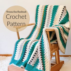 May include: A crocheted blanket with stripes of teal, white, gray, and gold yarn. The blanket is draped over a wooden rocking chair. The text "BrennaAnnHandmade Crochet Pattern" is visible in the image.