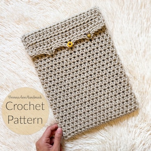 Könnte beinhalten: Ein beigefarbenes Häkelmuster für eine Tablethülle mit einem gewellten Rand und drei gelben Knöpfen. Das Muster liegt auf einer weißen, flauschigen Oberfläche. Der Text "BrennaAnnHandmade Crochet Pattern" befindet sich auf einem Holzkreis.