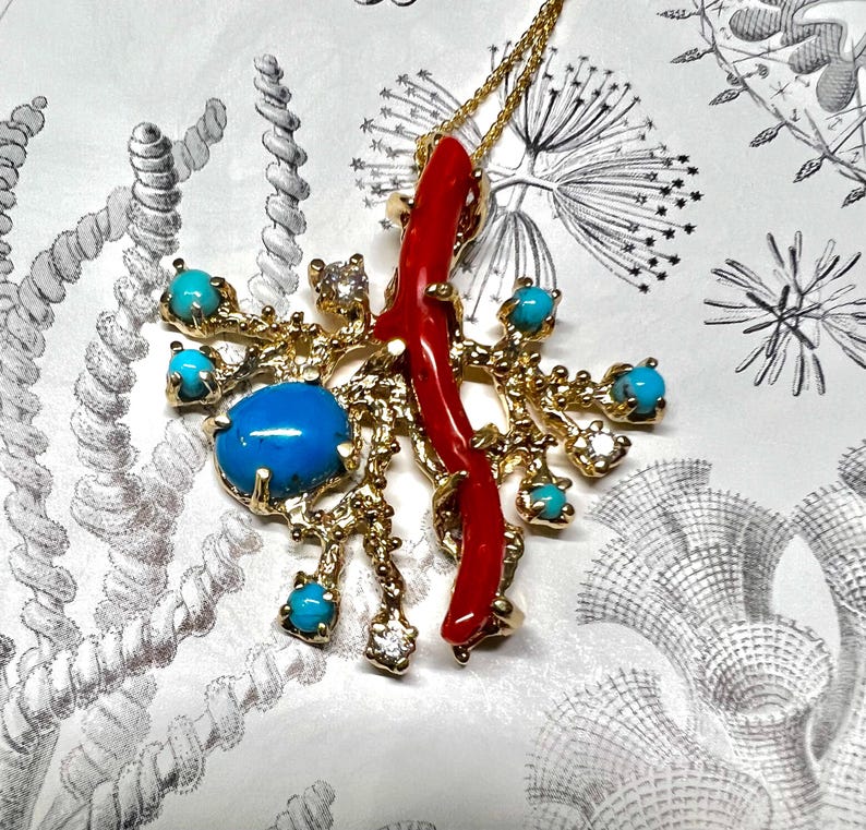 May include: A gold pendant necklace with a coral branch and turquoise stones. The pendant is shaped like a tree branch with a coral branch in the center. The pendant is surrounded by turquoise stones.