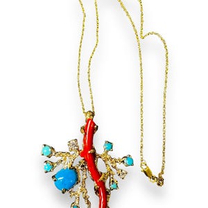 May include: A gold chain necklace with a pendant featuring a red coral branch, turquoise stones, and diamonds. The pendant is shaped like a tree branch with a coral branch growing from it.
