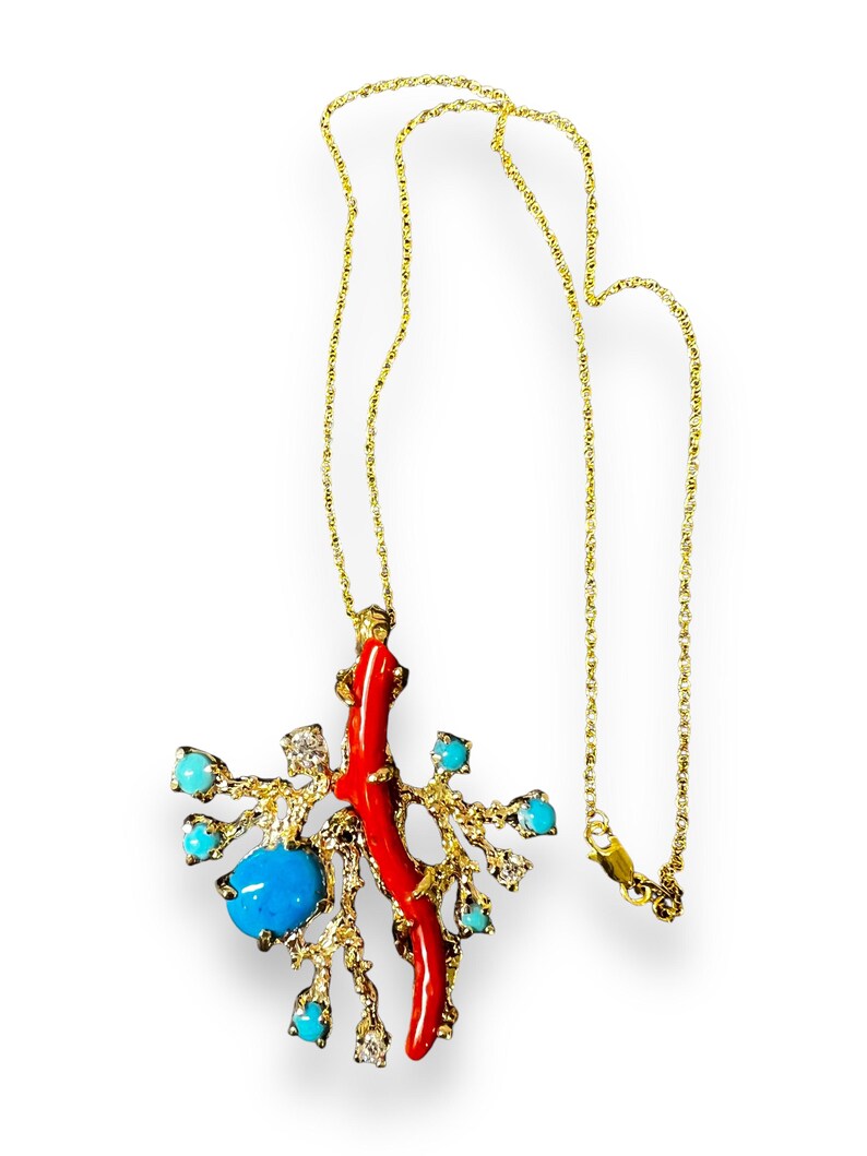 May include: A gold chain necklace with a pendant featuring a red coral branch, turquoise stones, and diamonds. The pendant is shaped like a tree branch with a coral branch growing from it.