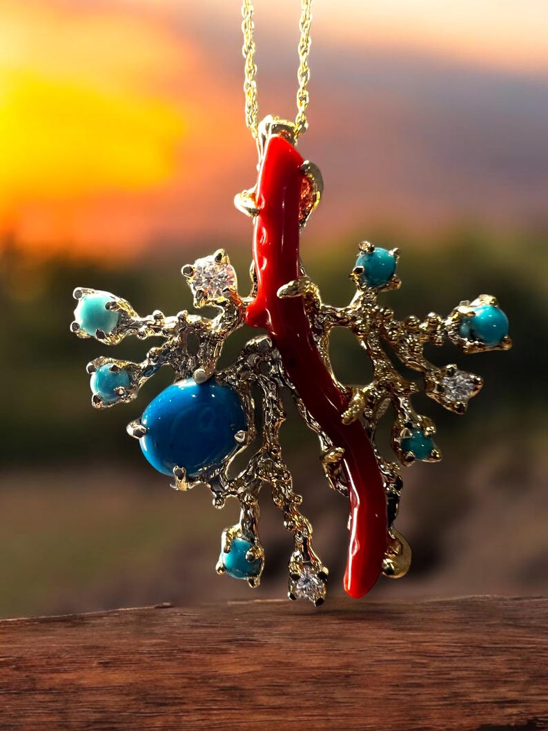 May include: A gold pendant necklace with a red coral branch and turquoise gemstones. The pendant is shaped like a tree with branches and leaves.