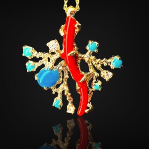 May include: A gold necklace with a pendant featuring a red coral branch and turquoise stones. The pendant is designed to resemble a coral reef.