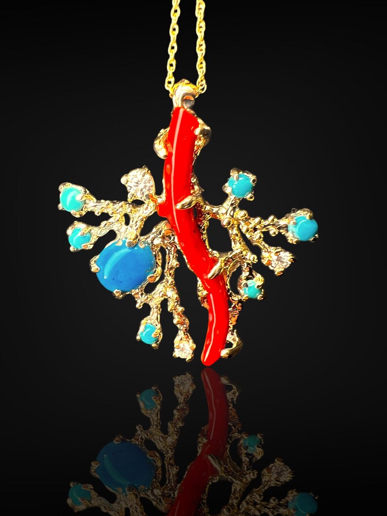 May include: A gold necklace with a pendant featuring a red coral branch and turquoise stones. The pendant is designed to resemble a coral reef.