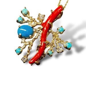 May include: A gold necklace with a pendant featuring a red coral branch and turquoise stones. The pendant is shaped like a tree branch with a textured surface.