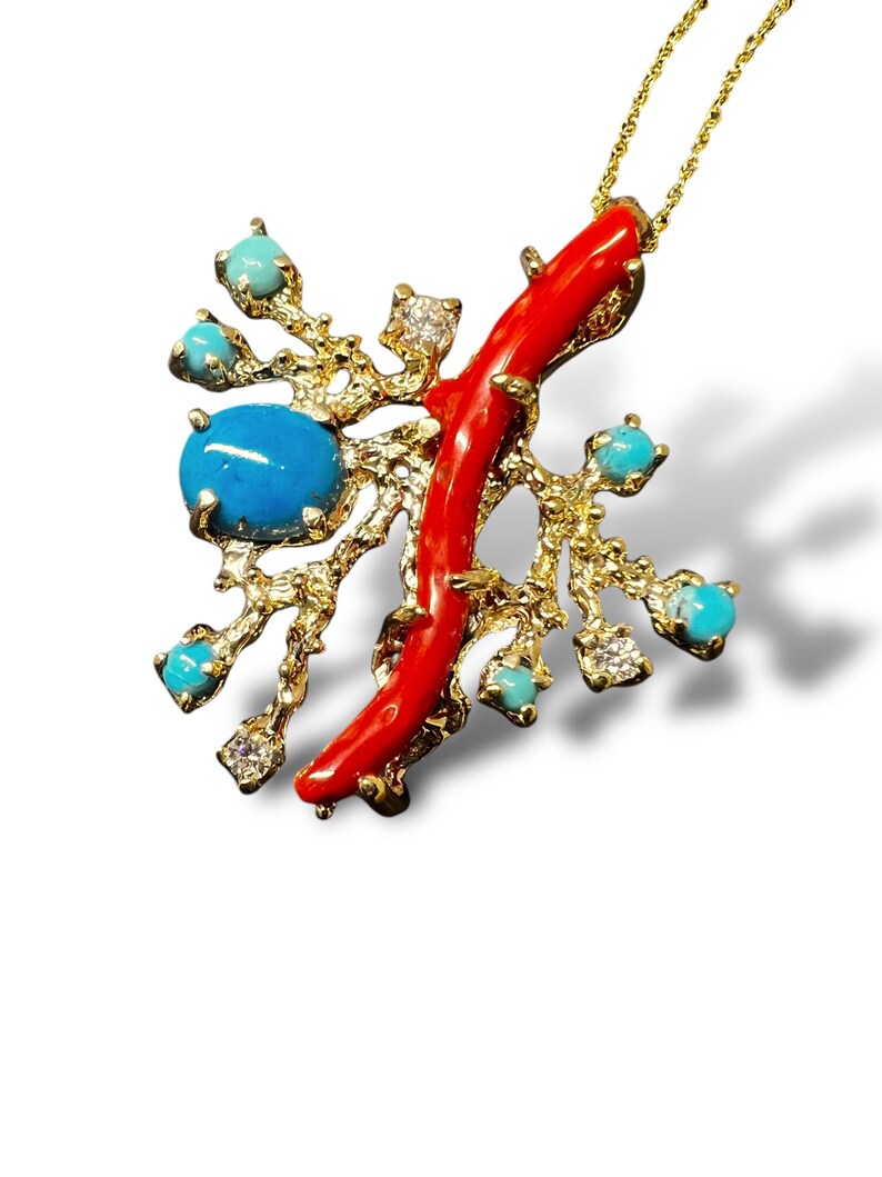 May include: A gold necklace with a pendant featuring a red coral branch and turquoise stones. The pendant is shaped like a tree branch with a textured surface.