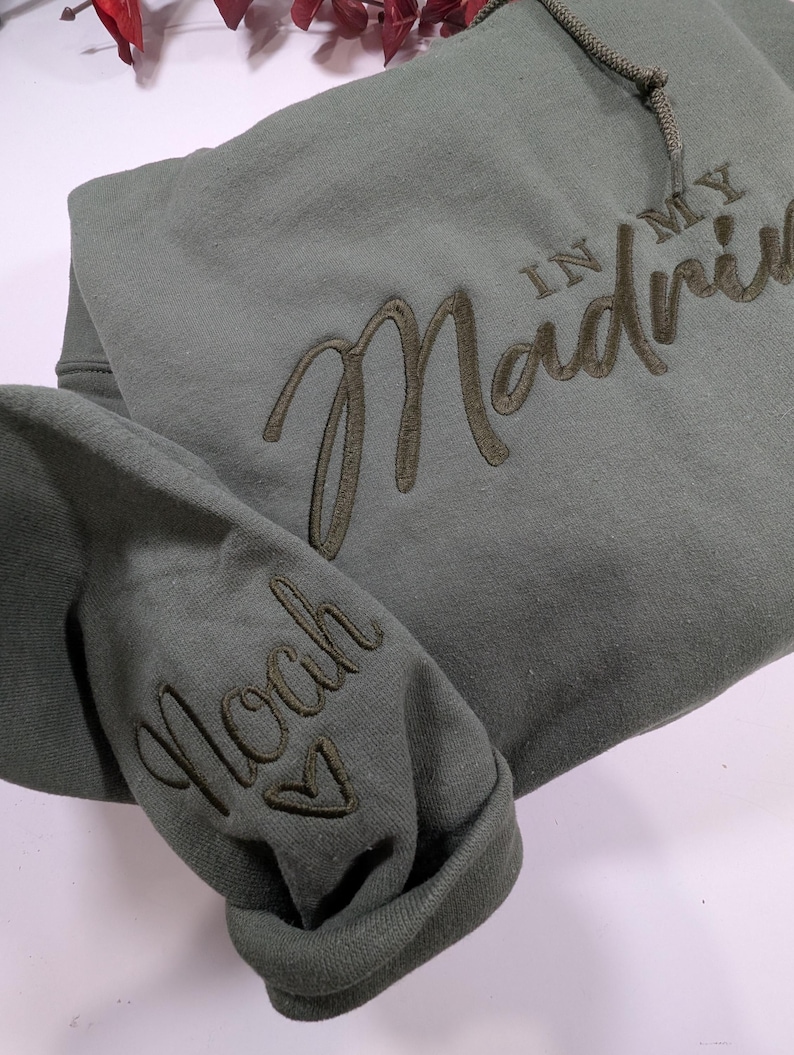 May include: A green hooded sweatshirt with the text "In My Madness" embroidered on the front and "Noah" embroidered on the sleeve.