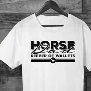 May include: White t-shirt with black text that reads "HORSE Dad Keeper of Wallets" with a horse head icon.