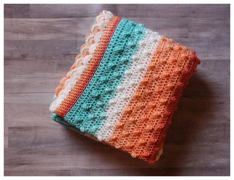 May include: A crocheted baby blanket with a textured stitch pattern. The blanket is made in shades of orange, white, and teal.