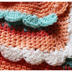 May include: A crocheted blanket with a multi-colored striped pattern and a scalloped edge. The blanket is made with different shades of orange, white, and turquoise yarn.
