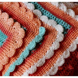 May include: A crocheted blanket with a scalloped edge in shades of peach, coral, turquoise, and white.