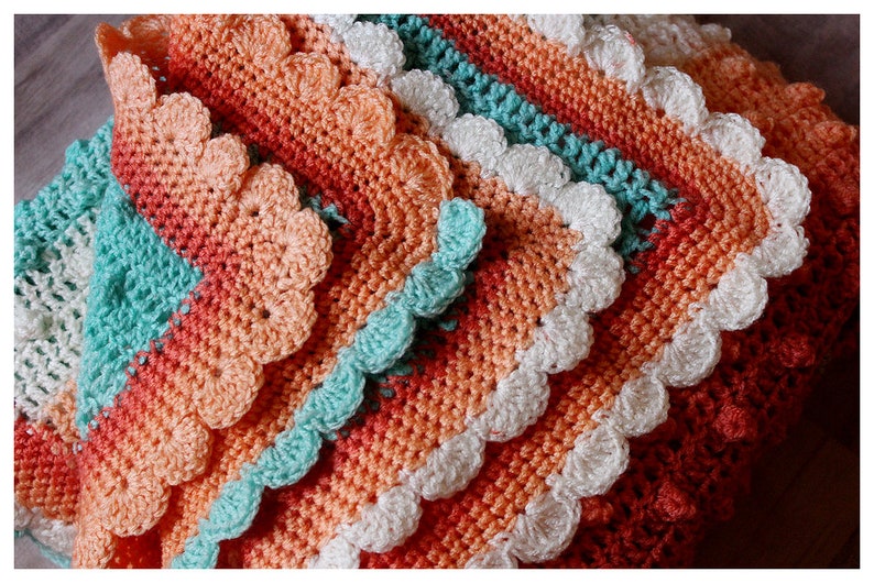 May include: A crocheted blanket with a scalloped edge in shades of peach, coral, turquoise, and white.