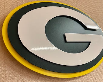 Puede incluir: Un logotipo "G" verde y blanco con un borde amarillo. El logotipo es un símbolo popular para un equipo deportivo.