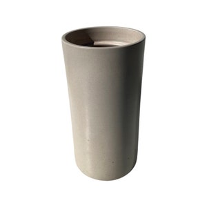 May include: A light gray ceramic vase with a cylindrical shape.