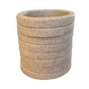 May include: A stack of beige, round, textured coasters. The coasters are made of a material that resembles stone.