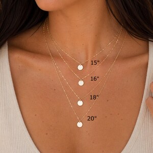 Pu&ograve; includere: Una collana dorata a strati con quattro catene di diverse lunghezze. Ogni catena presenta un piccolo ciondolo rotondo. Le lunghezze sono indicate come 15", 16", 18" e 20" pollici (38, 41, 46 e 51 cm).