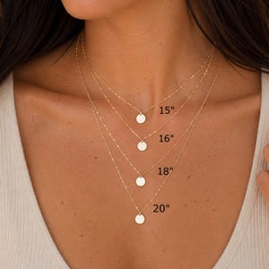 May include: Four layered gold necklaces, each featuring a small circular pendant. The chains are labeled with lengths of 15 inches, 16 inches, 18 inches, and 20 inches, indicating the specific drop length for each individual necklace in the set.