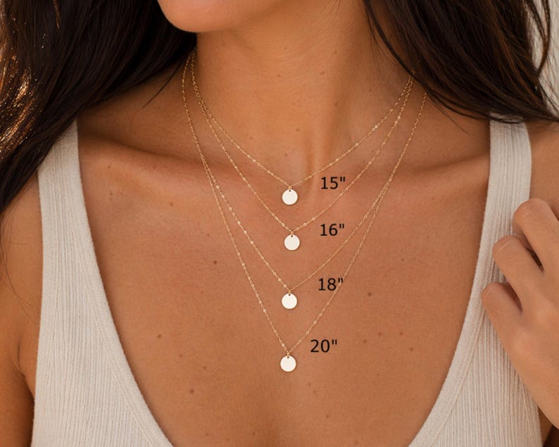 May include: Four layered gold necklaces, each featuring a small circular pendant. The chains are labeled with lengths of 15 inches, 16 inches, 18 inches, and 20 inches, indicating the specific drop length for each individual necklace in the set.