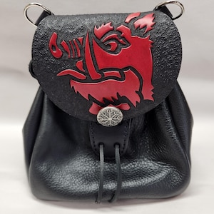 May include: Black leather pouch with a red boar design on the flap. The pouch has a drawstring closure and a decorative silver button. The bag has two silver rings at the top.