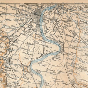 Puede incluir: Un mapa vintage de Colonia, Alemania, que muestra el diseño de la ciudad y las ciudades circundantes. El mapa está impreso en tinta negra, marrón y azul sobre un fondo crema. El mapa incluye una barra de escala y una clave.