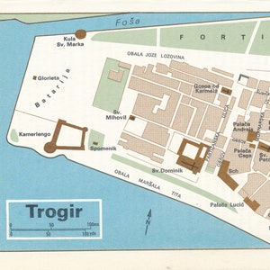 Puede incluir: Un mapa detallado de la ciudad croata de Trogir, que muestra la ubicación de varios puntos de referencia, incluida la fortaleza de Kamerlengo, la catedral y la torre del reloj. El mapa está impreso en un fondo azul claro con acentos marrones y beige.