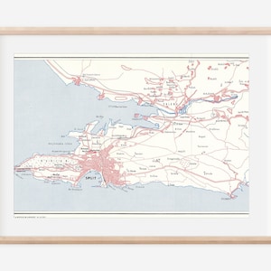 May include: A vintage map of Split, Croatia, with red and blue lines showing roads and waterways. The map is framed in a light wood frame.