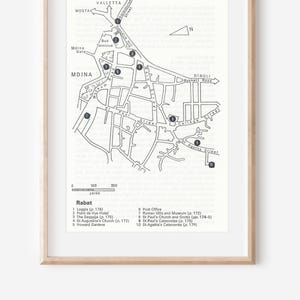 Può includere: Stampa di mappa in bianco e nero incorniciata di Mdina, Malta, con punti di interesse etichettati. La mappa include nomi di strade e una barra di scala. La stampa è in una cornice di legno chiaro.