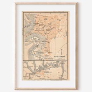 May include: A framed vintage map print of Rothenburg featuring a light tan background with black text and lines. The map displays detailed city layouts and geographical features, including a river, all enclosed in a simple light wood frame.