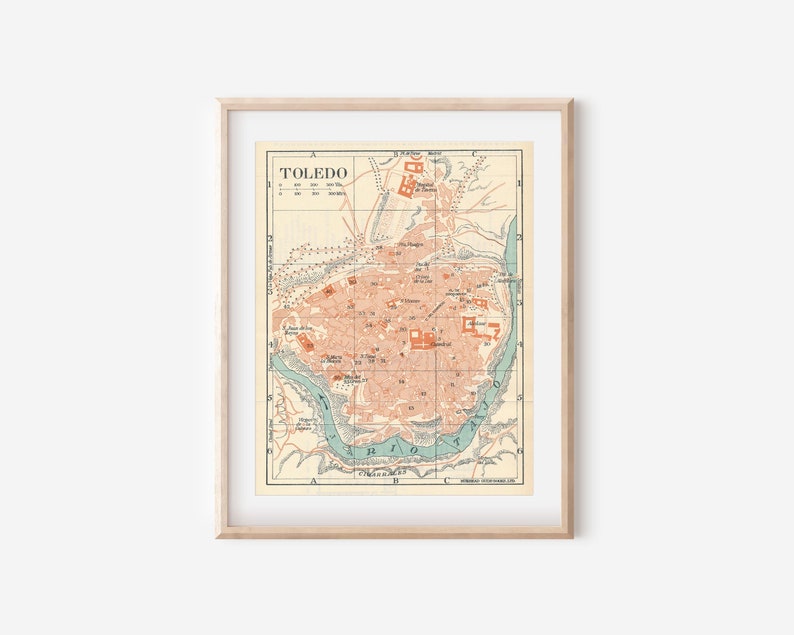 May include: A vintage map of Toledo, Spain, printed in shades of brown, green, and blue. The map shows the city's streets, buildings, and landmarks, including the Alcazar and the Cathedral. The map is framed in a light wood frame.