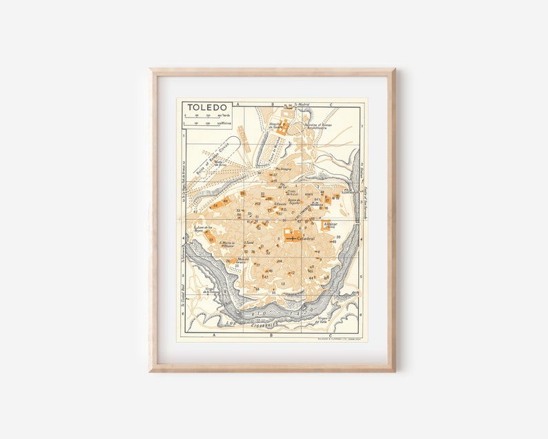 May include: A vintage map of Toledo, Spain, with a beige background and orange and gray markings. The map shows the city's streets, buildings, and landmarks. The title "TOLEDO" is printed in black at the top of the map.
