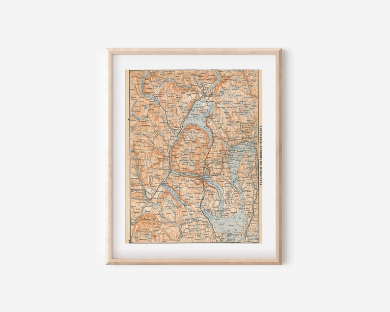 K&ouml;nnte beinhalten: Eine Vintage-Karte des Lake District in England, gerahmt in einem hellen Holzrahmen. Die Karte ist in Braun-, Blau- und Gr&uuml;nt&ouml;nen gedruckt, mit den Namen der St&auml;dte und D&ouml;rfer in Schwarz.