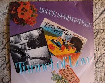 May include: A vintage record album cover featuring Bruce Springsteen. The album cover is purple with white text that reads "Bruce Springsteen" and "Tunnel of Love". The album cover also features a cartoon image of people riding a rollercoaster through a tunnel with the text "Tunnel of Love" and "Looking Forward to a Thrilling Time!"