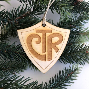 May include: Wooden Christmas ornament shaped like a shield with the letters "CTR" and a cross inside a heart.