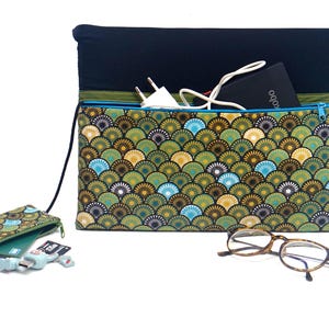 Op de afbeelding: Een laptophoes en een bijpassend klein etui met een waaierpatroon in groen, blauw en goud. De hoes heeft een zwarte bovenkant en een rits. Een bril en een oplader zijn ook zichtbaar.
