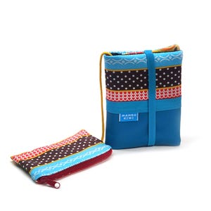 Peut inclure: Un sac bandoulière bleu et une pochette zippée assortie. Le sac présente un motif à pois blancs, des accents rouges et bleus. La pochette a une fermeture éclair rouge. Le texte "MAMBO KIWI" est sur le sac.