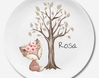 Puede incluir: Un plato de cerámica blanco con un árbol marrón y un zorro con una corona de flores rosas. El texto "Rosa" está escrito en el plato.