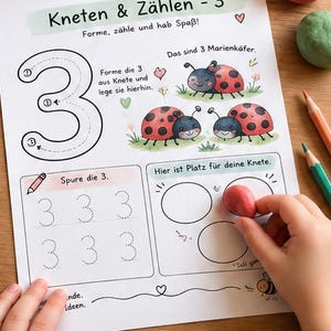 Op de afbeelding: Een wit educatief werkblad getiteld Kneten & Zählen - 3 met een groot cijfer 3, drie geïllustreerde lieveheersbeestjes, overtrek-oefeningen voor het cijfer 3 en een vak voor het plaatsen van boetseerklei op een houten ondergrond.