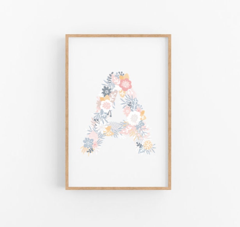 Puede incluir: Una impresi&oacute;n enmarcada con la letra A formada por flores de color rosa pastel, azul y amarillo. El fondo es blanco.