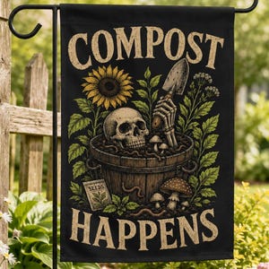 Könnte beinhalten: Eine schwarze Gartenflagge mit dem Text COMPOST HAPPENS in beiger Schrift. Das Motiv zeigt einen menschlichen Schädel in einem Holzeimer, eine Skeletthand mit einer Handschaufel, eine Sonnenblume, grünes Blattwerk, Pilze und eine Samentüte.