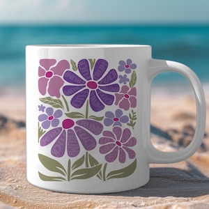 May include: White ceramic mug with a floral design. The flowers are purple and pink with the word "TRUMP" written on the petals.