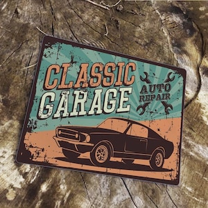 Puede incluir: Un letrero de metal de estilo vintage con un fondo desgastado que presenta un coche clásico y el texto "CLASSIC GARAGE AUTO REPAIR". El letrero tiene una combinación de colores azul, verde y naranja.