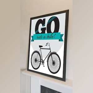 Puede incluir: Ilustración en blanco y negro de una bicicleta con el texto "GO ride a bike!" en una pancarta azul turquesa. El fondo es un círculo gris claro.