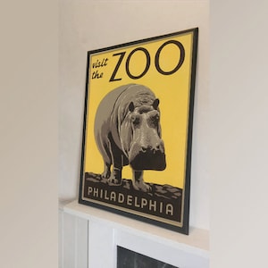 Puede incluir: Un cartel de estilo vintage que anuncia el zoológico de Filadelfia. El cartel presenta un fondo amarillo con el texto "visit the ZOO" en letras negras. Un hipopótamo marrón se presenta en el centro del cartel, con el texto "PHILADELPHIA" en la parte inferior.
