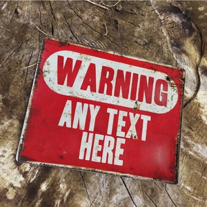 Puede incluir: Un letrero de metal rojo con texto blanco que dice "WARNING ANY TEXT HERE". El letrero tiene un aspecto desgastado y oxidado.