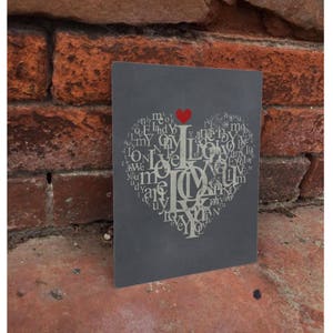 Puede incluir: Un letrero de metal gris con un diseño en forma de corazón hecho con la palabra "love" repetida muchas veces. El corazón está delineado en rojo.