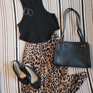 Op de afbeelding: Een zwart tanktop met een luipaardprint rok, een zwarte leren handtas en twee paar zwarte schoenen.
