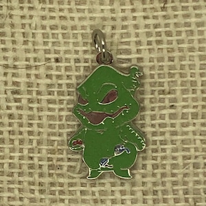 May include: A green, enamel charm of a character from the movie The Nightmare Before Christmas. The character is wearing a red and blue outfit and has a mischievous grin.