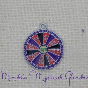 May include: A silver charm in the shape of a wheel of fortune with red, black, and purple sections. Each section has a different symbol, including a hand, a snake, a spider, and a skull.