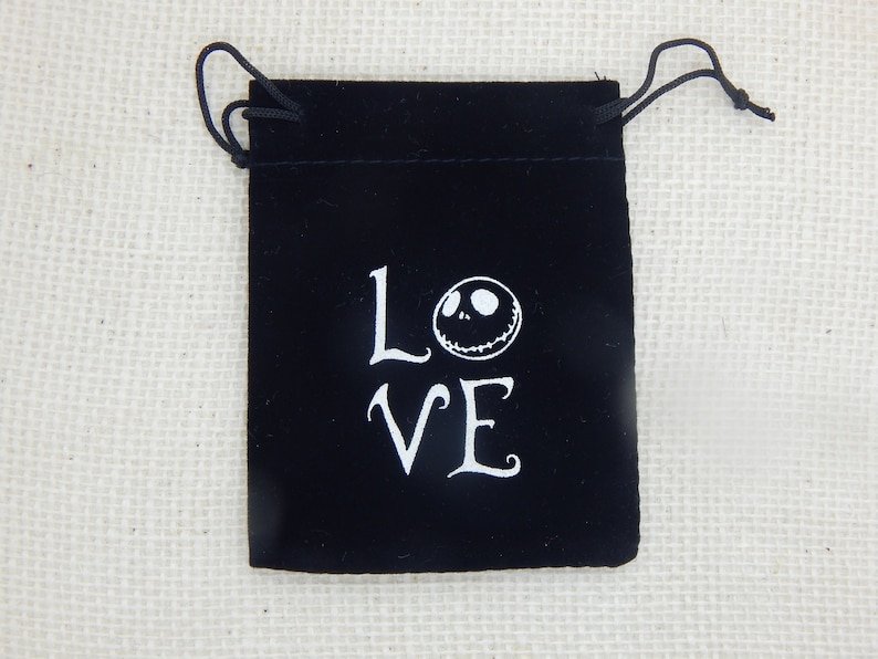 May include: Black velvet drawstring bag with white lettering that says "LOVE" and a white Jack Skellington face.